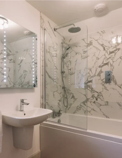 An Dòbhran upstairs en-suite bathroom with marble tiling, full-size bath with rain and hand held showers, White Company towels.