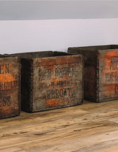 An Iolaire 3 antique wooden lemonade crates, from Aberdeen, Inverness and Arbroath on the chestnut wood flooring